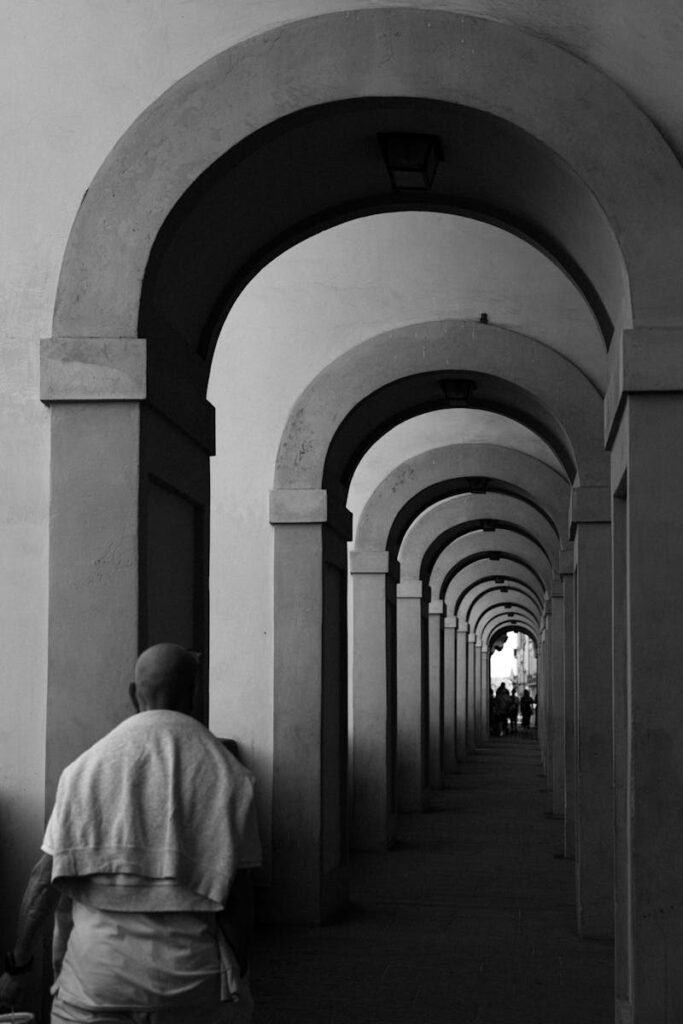 A striking black and white photo of an arched corridor in Florence, Italy, highlighting symmetry and depth.